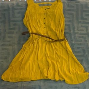 Gold sleeveless dress with brown belt .